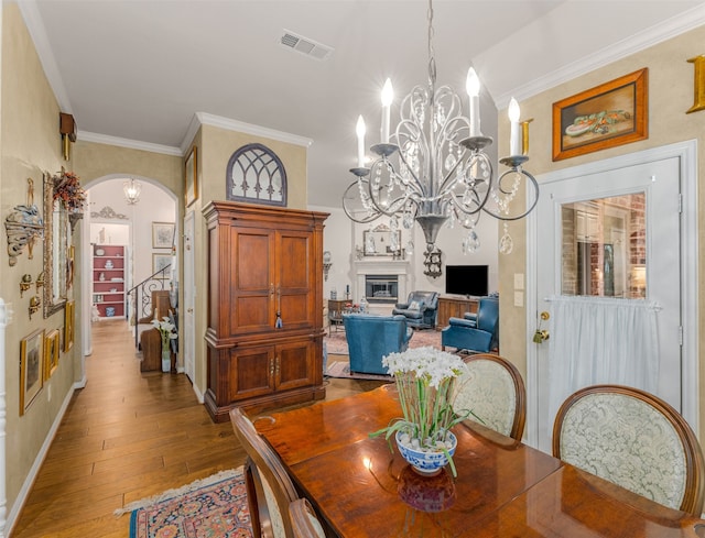 dining area featuring a notable chandelier, hardwood / wood-style flooring, and ornamental molding