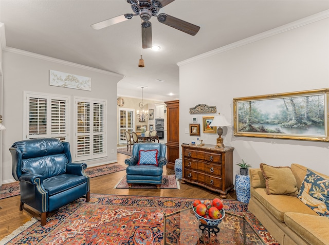 living room with hardwood / wood-style flooring, ornamental molding, and ceiling fan with notable chandelier