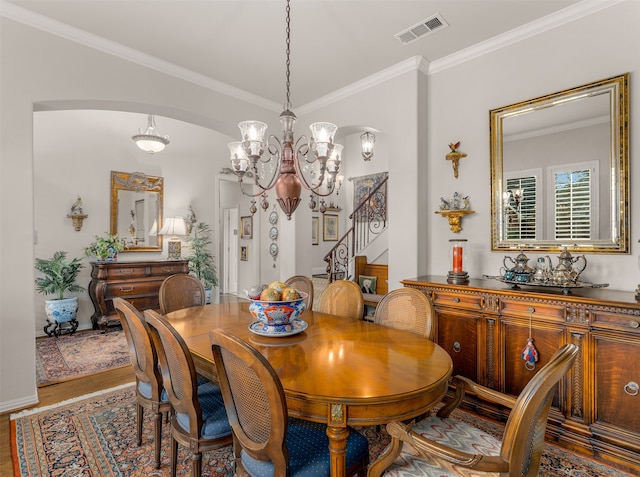 dining area with hardwood / wood-style flooring, ornamental molding, and a chandelier