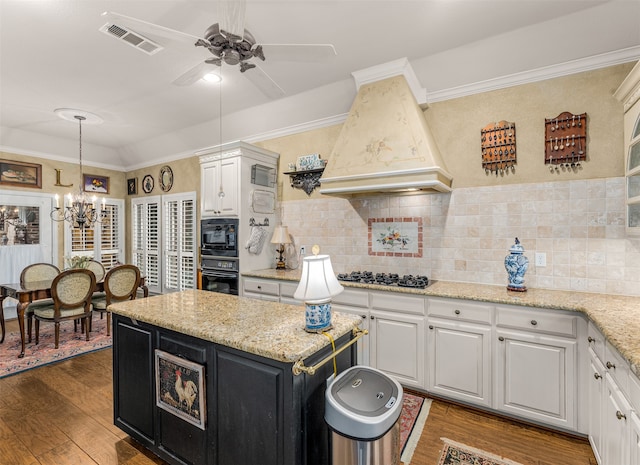 kitchen featuring stainless steel gas cooktop, dark hardwood / wood-style floors, custom exhaust hood, white cabinetry, and tasteful backsplash