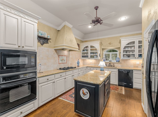 kitchen with white cabinetry, hardwood / wood-style flooring, black appliances, and a center island