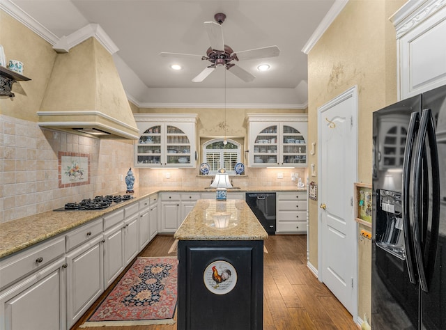 kitchen featuring wood-type flooring, black appliances, a center island, custom exhaust hood, and ornamental molding