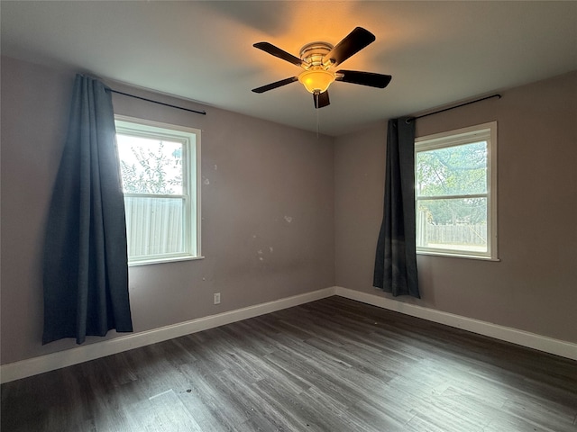 empty room with a healthy amount of sunlight, dark wood-type flooring, and ceiling fan