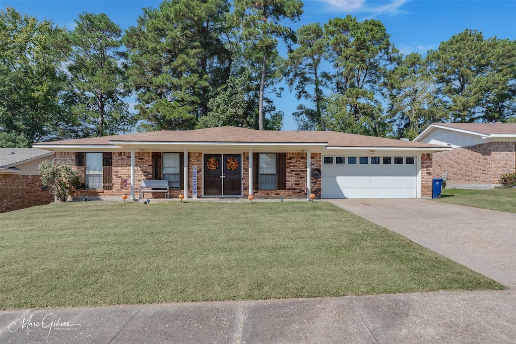 single story home featuring a garage, a front lawn, and a porch