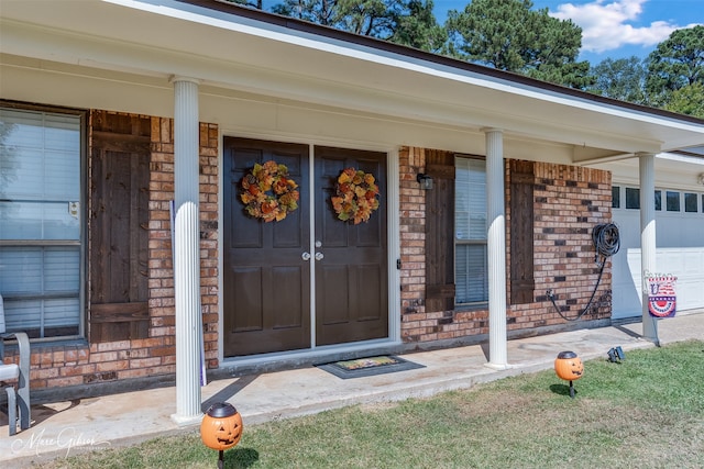 view of exterior entry featuring a porch and a garage