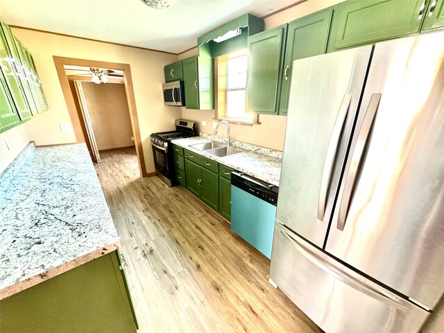 kitchen with ceiling fan, appliances with stainless steel finishes, light hardwood / wood-style flooring, sink, and green cabinetry