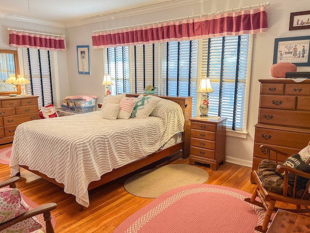 bedroom with ornamental molding, multiple windows, and hardwood / wood-style flooring