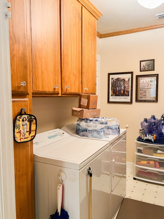 laundry area with crown molding, washing machine and dryer, and cabinets