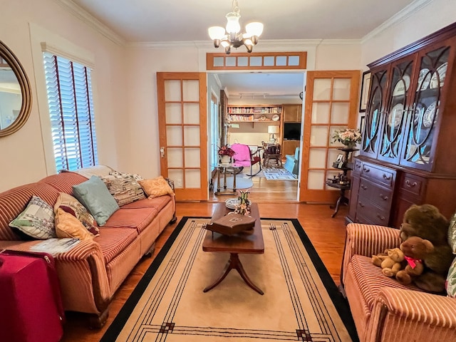 living room featuring french doors, hardwood / wood-style flooring, ornamental molding, and a chandelier