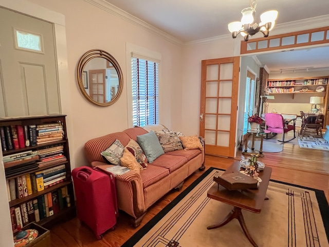 living room featuring an inviting chandelier, ornamental molding, hardwood / wood-style floors, and french doors