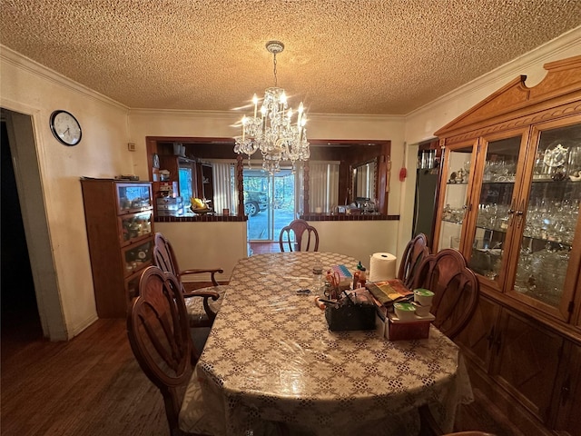 dining space with a textured ceiling, a notable chandelier, wood finished floors, and crown molding