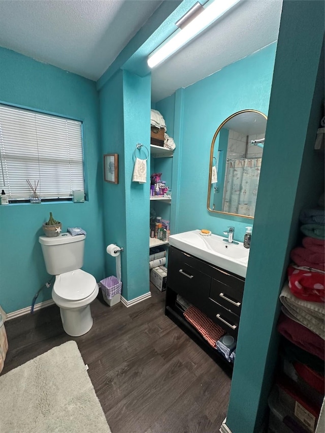 bathroom with toilet, vanity, baseboards, and wood finished floors
