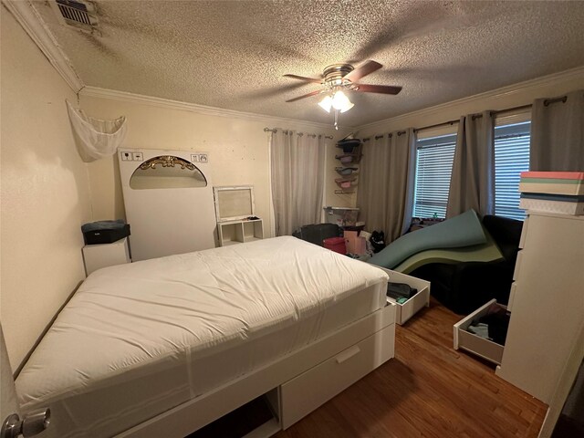 bedroom with ornamental molding, a textured ceiling, and wood finished floors