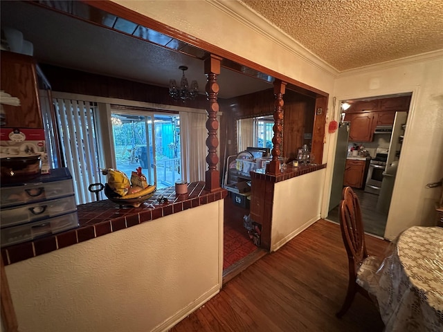 dining space with dark wood finished floors, an inviting chandelier, ornamental molding, and a textured ceiling