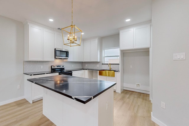 kitchen featuring white cabinets, light hardwood / wood-style flooring, sink, pendant lighting, and stainless steel appliances