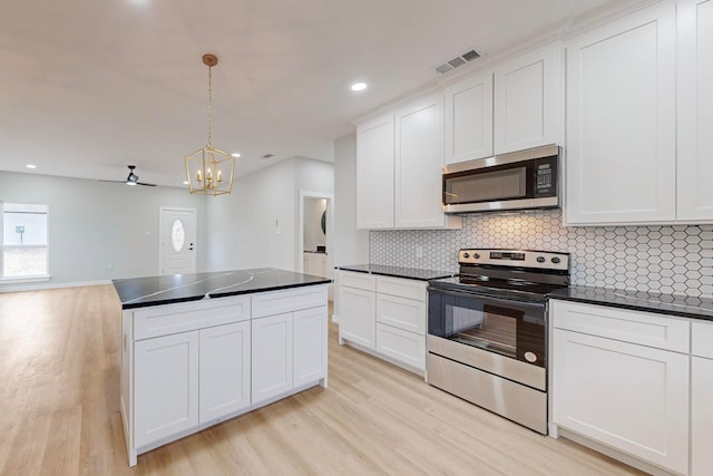 kitchen with white cabinetry, stainless steel appliances, hanging light fixtures, and light wood-type flooring