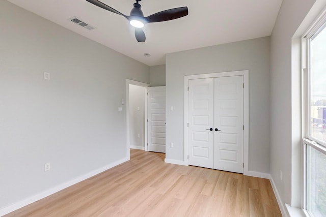 unfurnished bedroom featuring a closet, ceiling fan, multiple windows, and light wood-type flooring