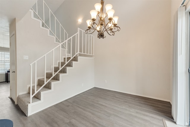 staircase with hardwood / wood-style flooring and a chandelier