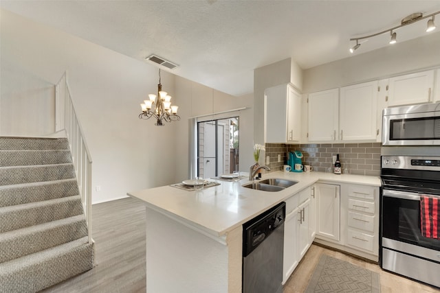 kitchen with pendant lighting, kitchen peninsula, sink, white cabinetry, and appliances with stainless steel finishes