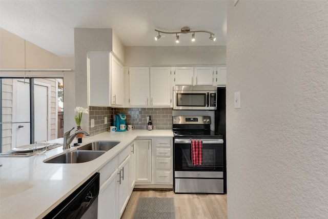 kitchen with sink, stainless steel appliances, white cabinets, decorative backsplash, and light wood-type flooring