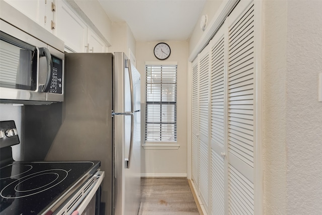 kitchen featuring light hardwood / wood-style flooring, appliances with stainless steel finishes, and white cabinets