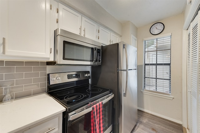 kitchen with backsplash, stainless steel appliances, light hardwood / wood-style flooring, and white cabinets