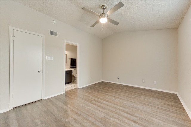 unfurnished bedroom featuring connected bathroom, vaulted ceiling, a textured ceiling, ceiling fan, and light hardwood / wood-style floors