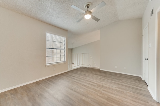 unfurnished room with ceiling fan, vaulted ceiling, a textured ceiling, and light hardwood / wood-style flooring