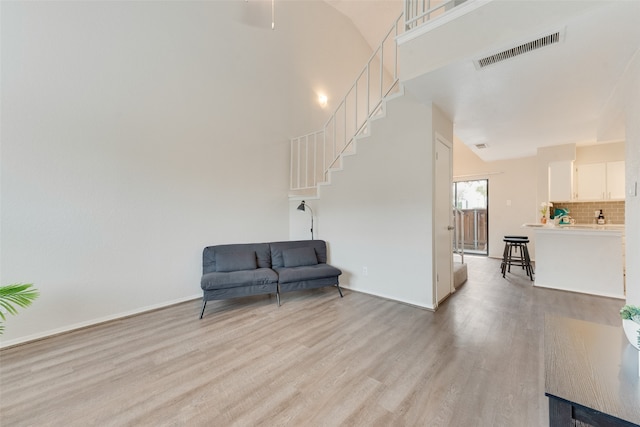 living area with a towering ceiling and light wood-type flooring