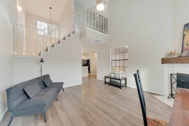 living area featuring high vaulted ceiling, wood-type flooring, and a tile fireplace