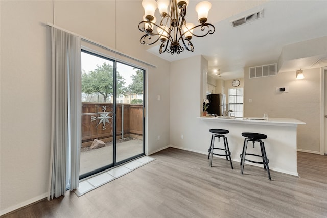 kitchen featuring light wood-type flooring, kitchen peninsula, stainless steel refrigerator, and a breakfast bar area