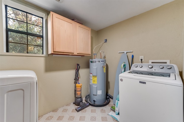 washroom featuring washing machine and dryer, electric water heater, and cabinets