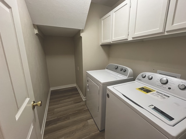 clothes washing area with washer and dryer, a textured ceiling, dark hardwood / wood-style flooring, and cabinets