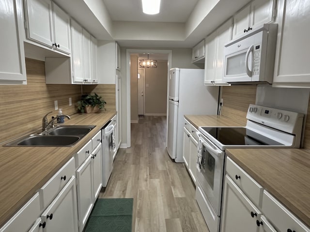 kitchen featuring white cabinets, white appliances, light hardwood / wood-style flooring, and sink