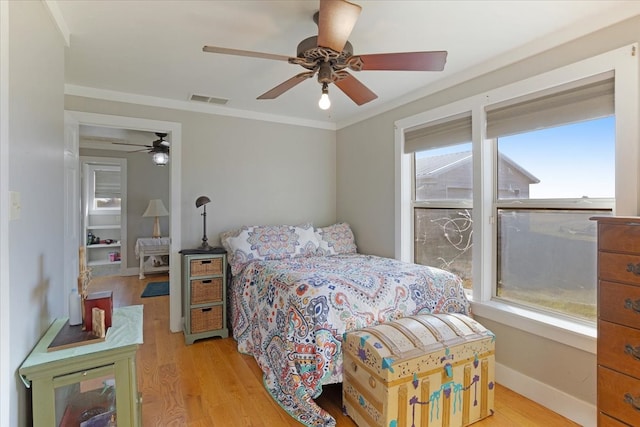 bedroom featuring multiple windows, ceiling fan, light hardwood / wood-style floors, and ornamental molding