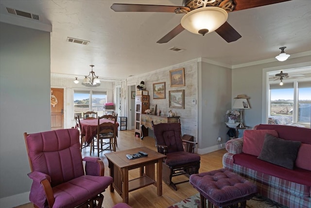 living room with light hardwood / wood-style floors, ornamental molding, and a chandelier