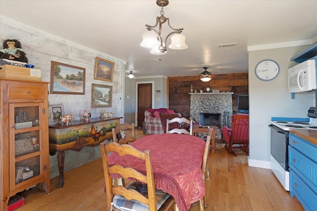 dining space with ceiling fan with notable chandelier, light hardwood / wood-style floors, and a fireplace