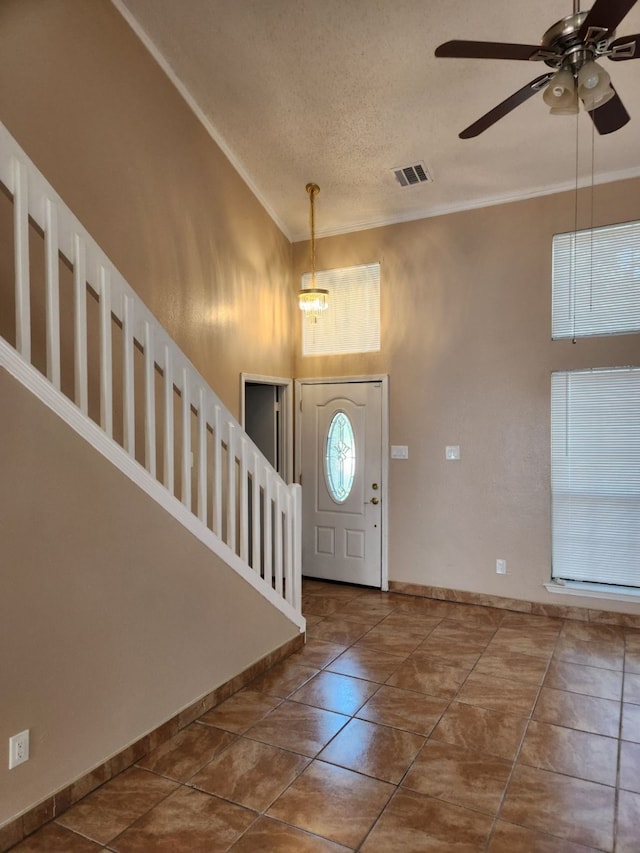 entryway with ornamental molding, a textured ceiling, and ceiling fan with notable chandelier