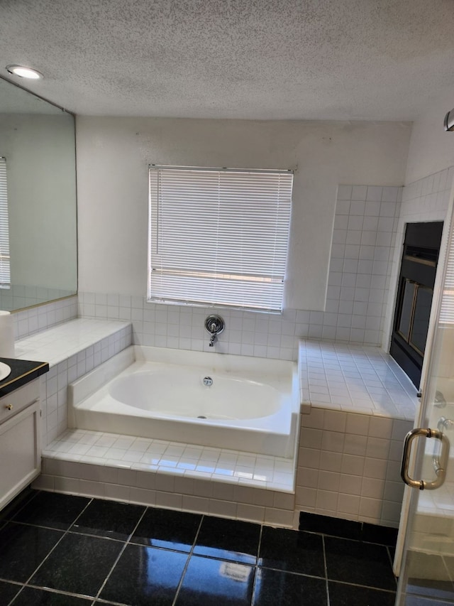 bathroom featuring vanity, tiled bath, a textured ceiling, and tile patterned flooring