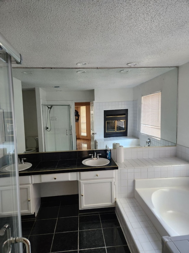 full bathroom featuring shower with separate bathtub, a textured ceiling, toilet, vanity, and tile patterned flooring