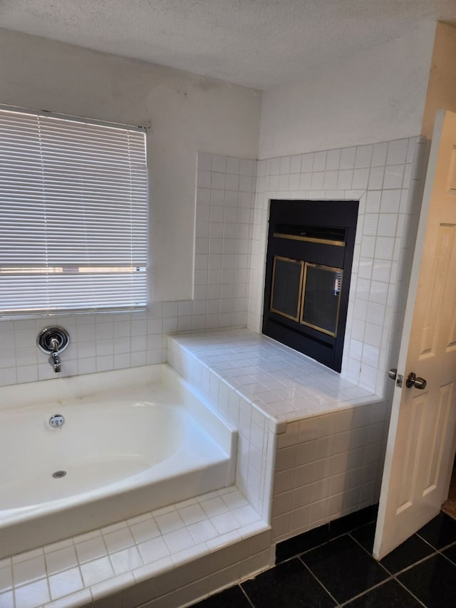 bathroom featuring tiled bath, tile patterned floors, and a textured ceiling