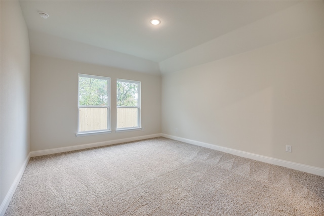 carpeted spare room featuring lofted ceiling