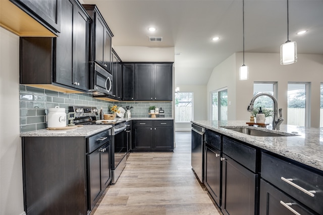 kitchen with appliances with stainless steel finishes, sink, pendant lighting, decorative backsplash, and light hardwood / wood-style flooring