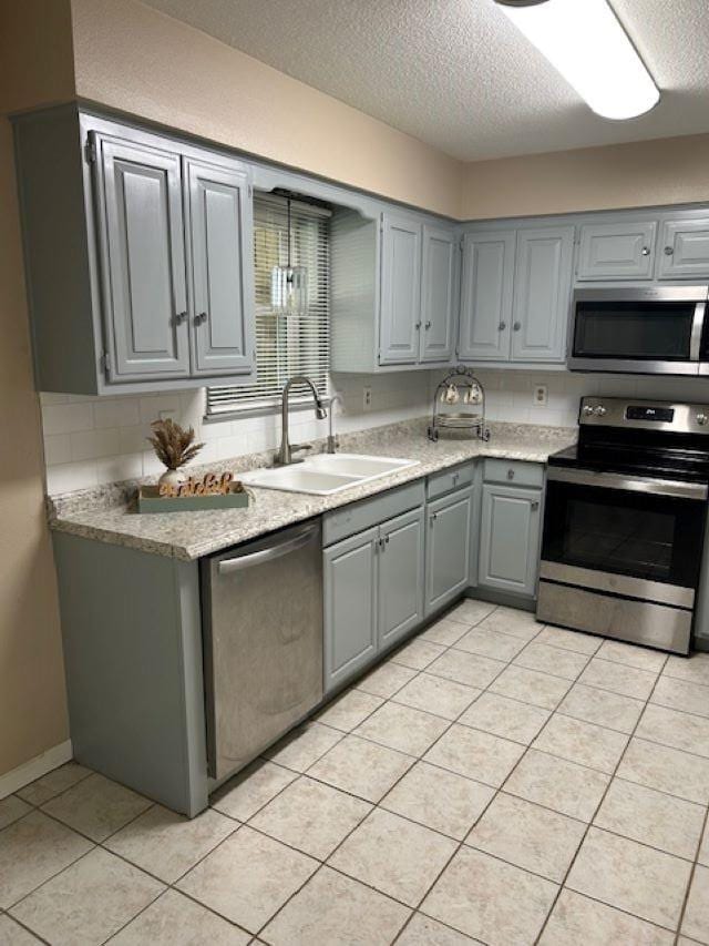 kitchen with sink, stainless steel appliances, gray cabinetry, and a textured ceiling