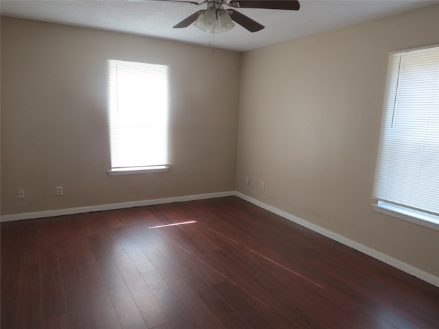 empty room featuring a healthy amount of sunlight, ceiling fan, and dark hardwood / wood-style floors