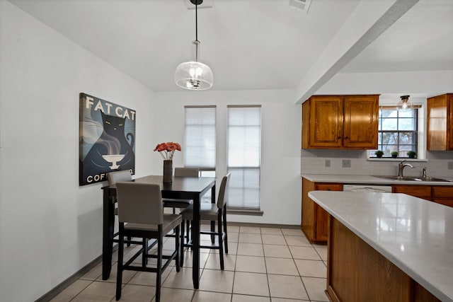 kitchen with decorative backsplash, light tile patterned floors, dishwasher, pendant lighting, and sink