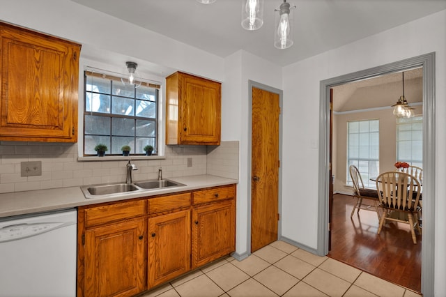 kitchen with decorative backsplash, white dishwasher, light wood-type flooring, sink, and decorative light fixtures