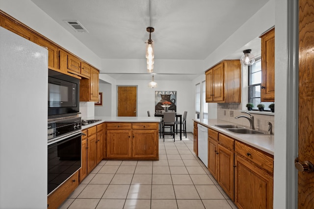 kitchen with kitchen peninsula, hanging light fixtures, sink, black appliances, and light tile patterned floors