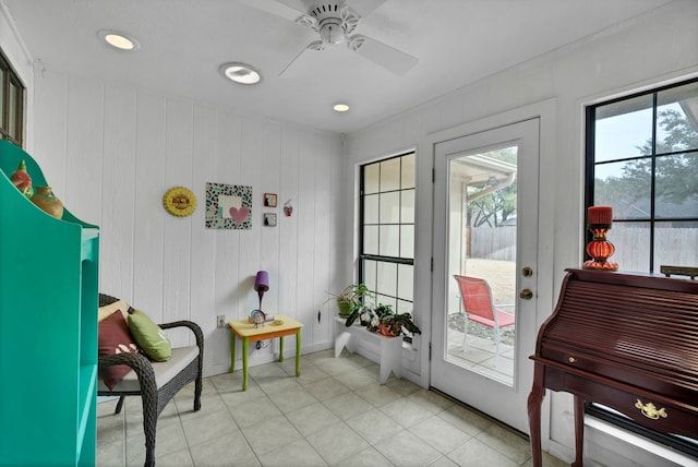 doorway to outside with light tile patterned flooring, wooden walls, and ceiling fan