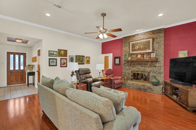 living room with ceiling fan, crown molding, a fireplace, and hardwood / wood-style floors